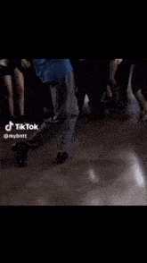 a man in a blue shirt is standing in front of a crowd of people dancing ..