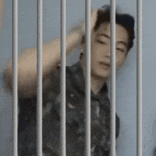 a man in a prison cell behind bars with his hand on his head