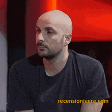a bald man with a beard wearing a black t-shirt with the website recenzionivere.com on the bottom right