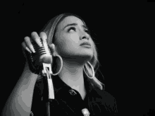 a black and white photo of a woman holding two microphone