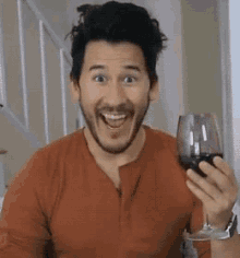 a man with a beard is holding a glass of red wine .