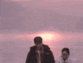 a man and a woman holding hands in front of a pink sky