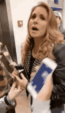 a woman is holding a cell phone in her hand and talking to someone .