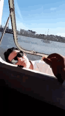 a man in sunglasses is looking out of a window at a body of water