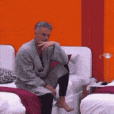 a man in a robe is sitting on a bed in a bedroom