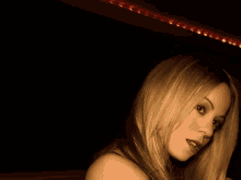 a woman with blonde hair is looking at the camera in a dark room