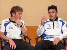 two men are sitting next to each other and one has a honda logo on his shirt