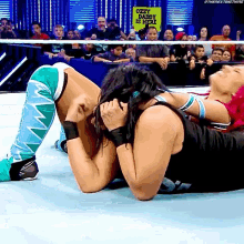 two women wrestling in front of a crowd with a sign that says " ozzy osbourne is here "