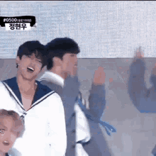 a group of young men are dancing on a stage while wearing sailor outfits .