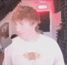 a man wearing a white shirt is standing in a room with a red light behind him .