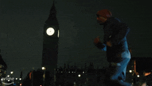 a man is running in front of big ben at night .