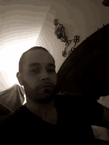 a man in a dark room with a clock on the wall that says 88