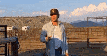 a man wearing a new york yankees hat is standing in a dirt field .