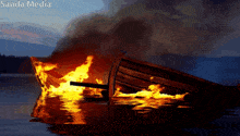a boat is burning in the water and the words sanda media are above it