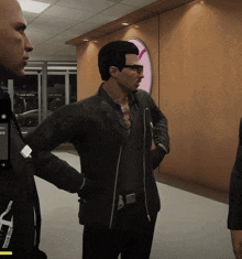 a man in a black jacket is standing next to a man in a black shirt and a man in a black jacket