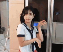 a girl in a sailor outfit is standing in front of a door