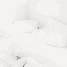 a bed with white sheets and pillows in a corner