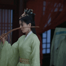 a woman in a green dress is holding a stick