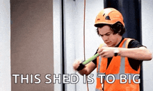 harry styles is wearing a hard hat and safety vest while measuring a piece of wood .