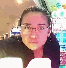 a woman wearing glasses and hoop earrings is looking at the camera