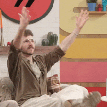 a man is sitting on a couch with his arms up in the air