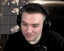 a man wearing headphones looks at something in front of a board with the number 7 on it