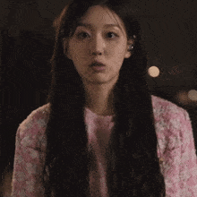 a woman wearing a pink and white sweater looks at the camera
