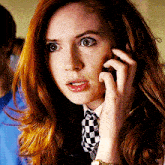 a woman wearing a checkered tie is talking on her cell phone