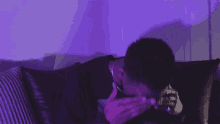 a person is sitting on a couch with a purple light behind them