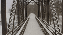 a bridge that is covered in snow and has a wooden railing
