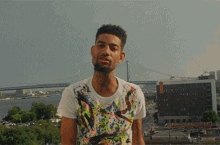a man in a colorful shirt stands in front of a city