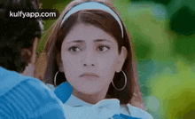 a man and a woman are looking at each other and the woman is wearing a headband and earrings .