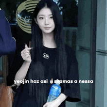 a woman with long black hair is holding a bottle of water and a chocolate bar .