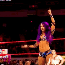 a woman with purple hair is in a wrestling ring with a man
