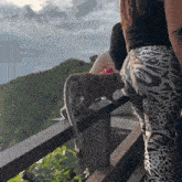 a woman standing next to a monkey on a railing