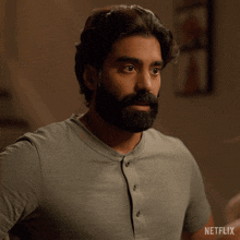 a man with a beard is wearing a grey shirt with netflix written on it