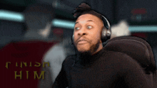 a man wearing headphones is standing in front of a finish him sign