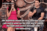 a woman is singing into a microphone while a man sits behind her holding a microphone .