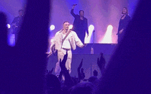 a group of people are standing on a stage with purple lights