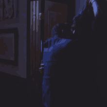 a man in a blue suit stands in a dark room
