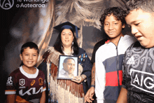 a woman in a graduation cap holds a picture of a man