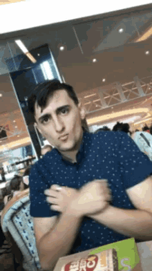 a man in a blue shirt is sitting at a table with a mcdonald 's box on the table