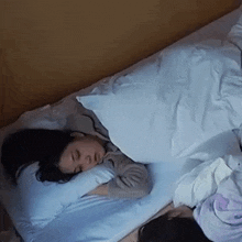 a woman is sleeping on a bed with a blue comforter
