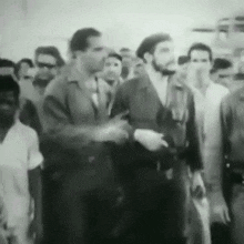 a black and white photo of a group of men standing together .