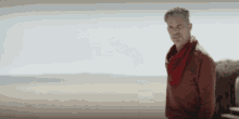 a man with a red scarf around his neck is standing in a desert