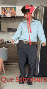 a man in a blue shirt and black pants is dancing in front of a refrigerator with the words que sabrosa written below him