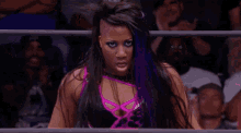 a female wrestler with purple hair is smiling and looking at the camera .