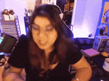a woman wearing glasses and a black shirt is sitting at a desk in front of a funko pop box