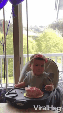 a baby is sitting in a high chair with a cake on a tray and the words viralhog below it