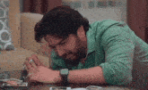 a man is laying on the floor crying while looking at a picture on a table .